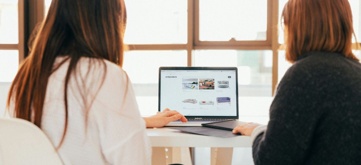 Two women working on a laptop, photo by KOBU Agency on Unsplash