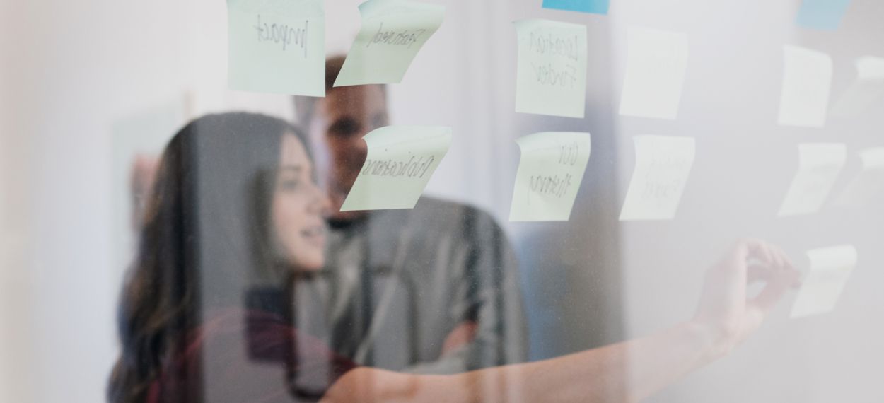 Woman using sticky notes on a transparent whiteboard