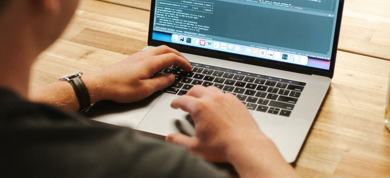 Software developer working on a laptop displaying code, sitting at a table