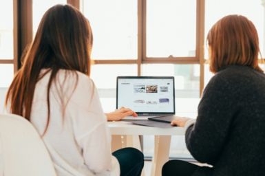 Two women working on a laptop, photo by KOBU Agency on Unsplash