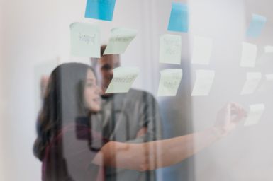 Woman using sticky notes on a transparent whiteboard