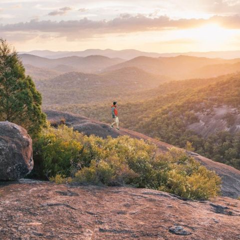 mountainous bush landscape during sunset with a person walking downhill