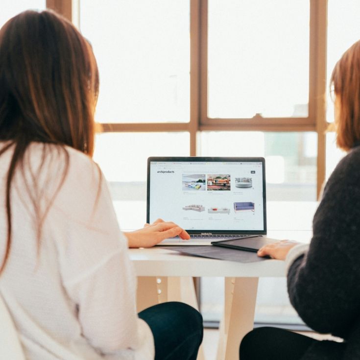 Two women working on a laptop, photo by KOBU Agency on Unsplash