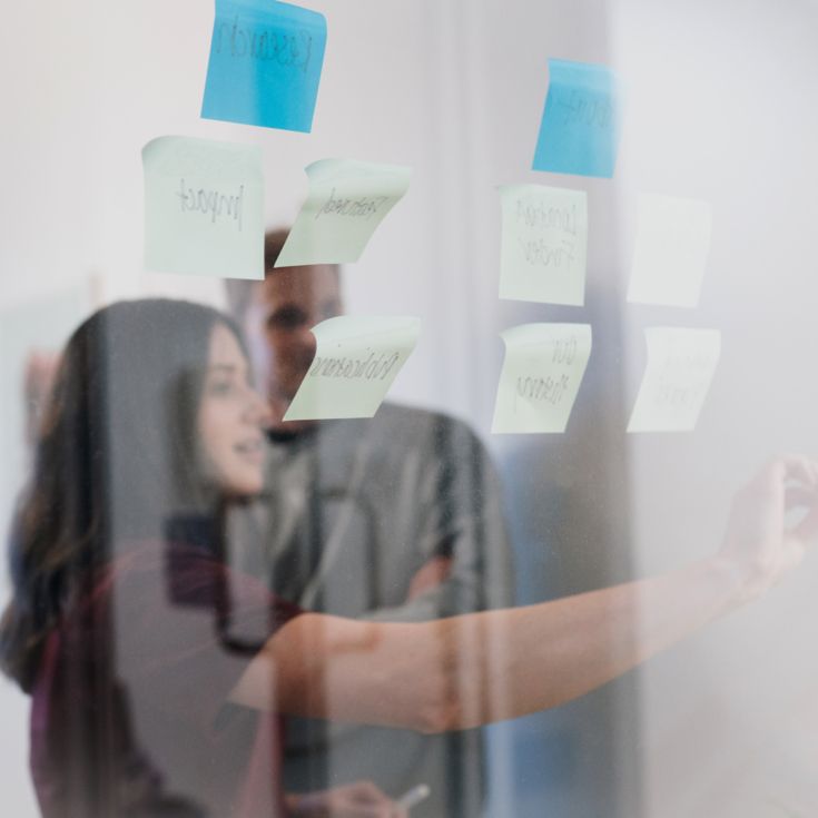 Woman using sticky notes on a transparent whiteboard