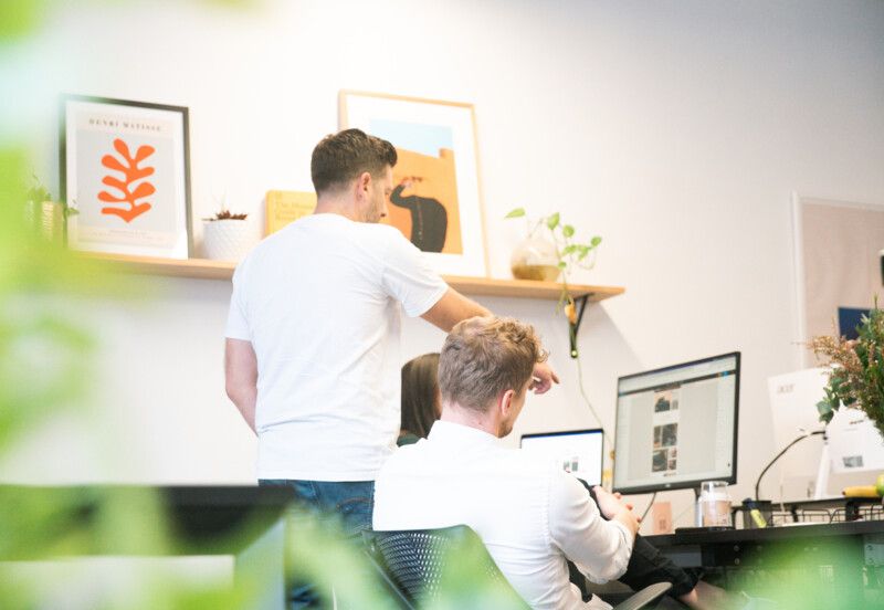 Colleagues discussing a project around a desktop in an office